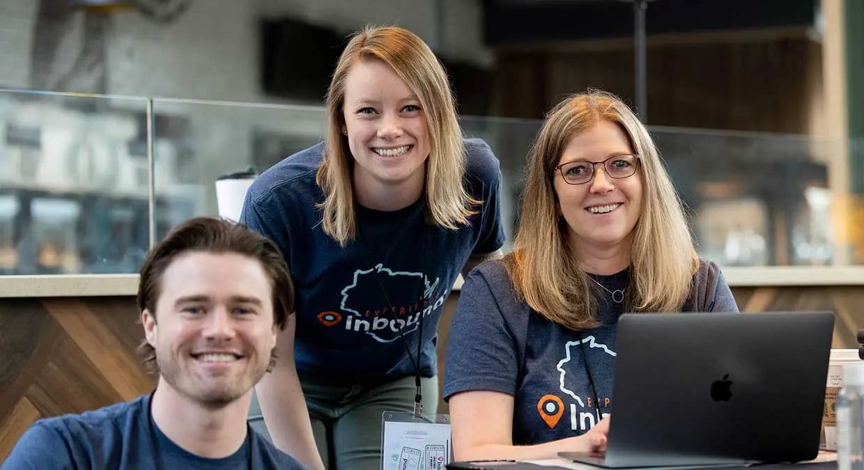 Three Weidert Group employees wearing Experience Inbound shirts with friendly smiles. 