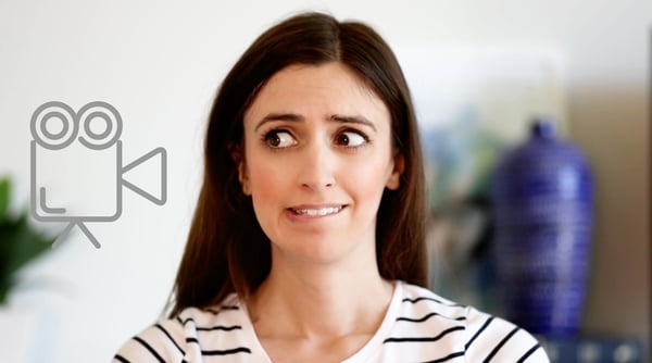 A nervous woman with a look of concern, biting her lip and looking to the side at video icon