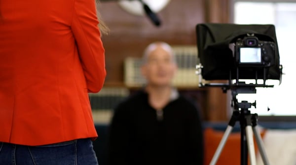 a scene from behind a video camera showing a business man being interviewed