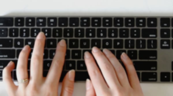 Woman’s fingers typing on a Mac keyboard