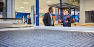 Business people talking in a display room of manufacturing equipment.