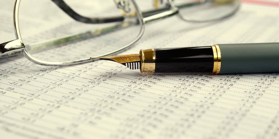 Fountain pen and glasses sitting on a paper with a table of numbers.
