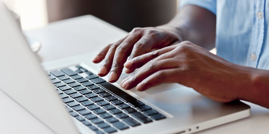 Hands typing on a laptop
