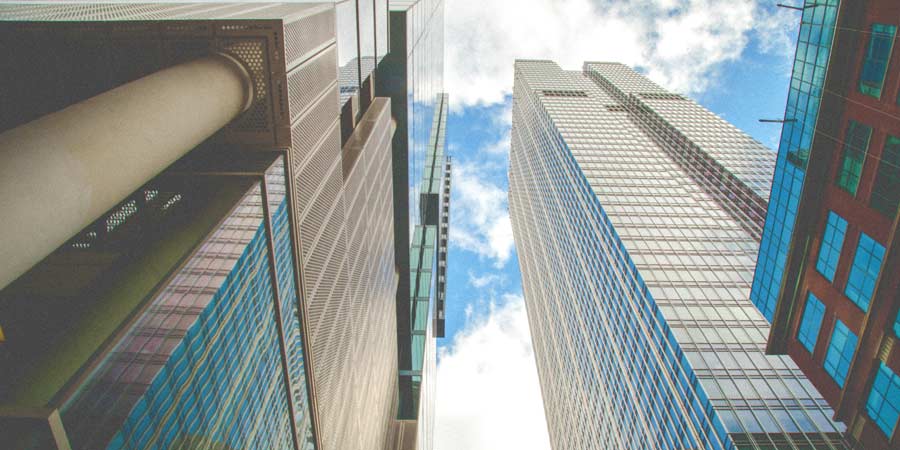 Looking up a skyscrapers and a blue sky with clouds.