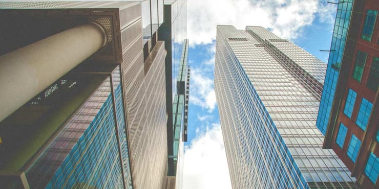 Looking up a skyscrapers and a blue sky with clouds.