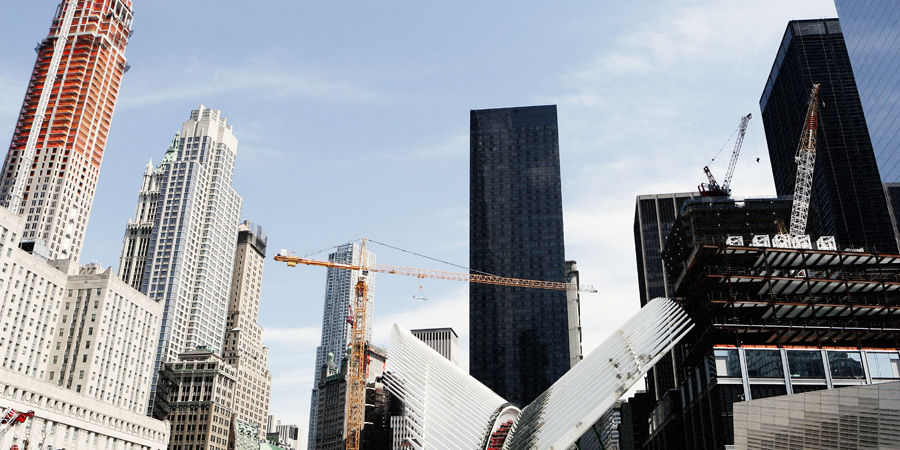 City skyline with several tall sky scrapers and construction cranes.