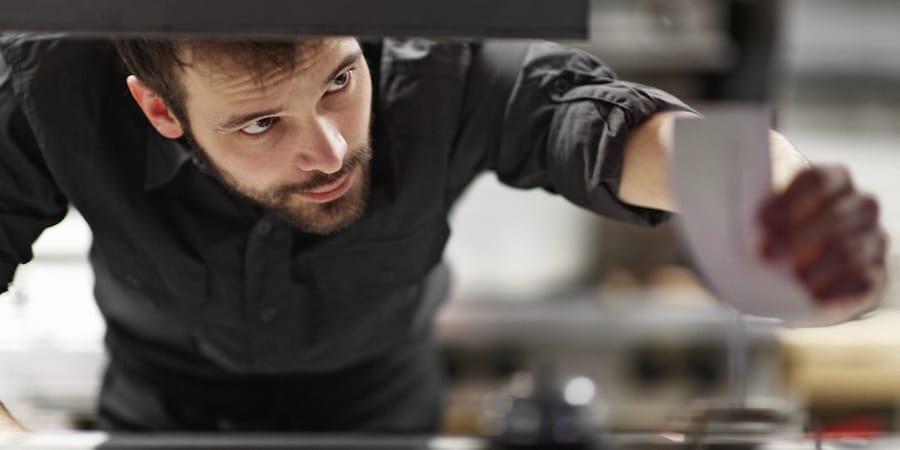 Person holding a tool and intently looking at it.