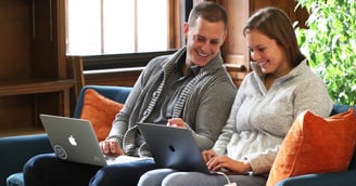 Two Weidert employees sitting on a couch working on laptops