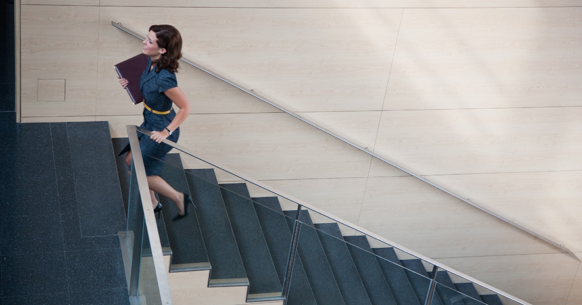 Person carrying a laptop walking up a flight of stairs.