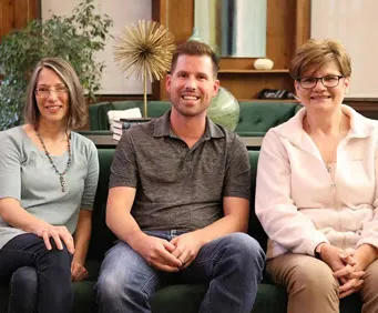Kate, Frank, and, Vicki sitting on a couch in the Weidert Group library