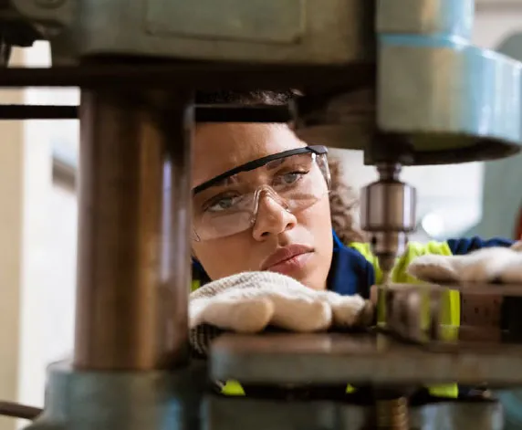 Manufacturing industry worker wearing safety glasses loading a drill press