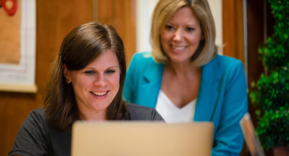 Weidert Group employees smiling at computer